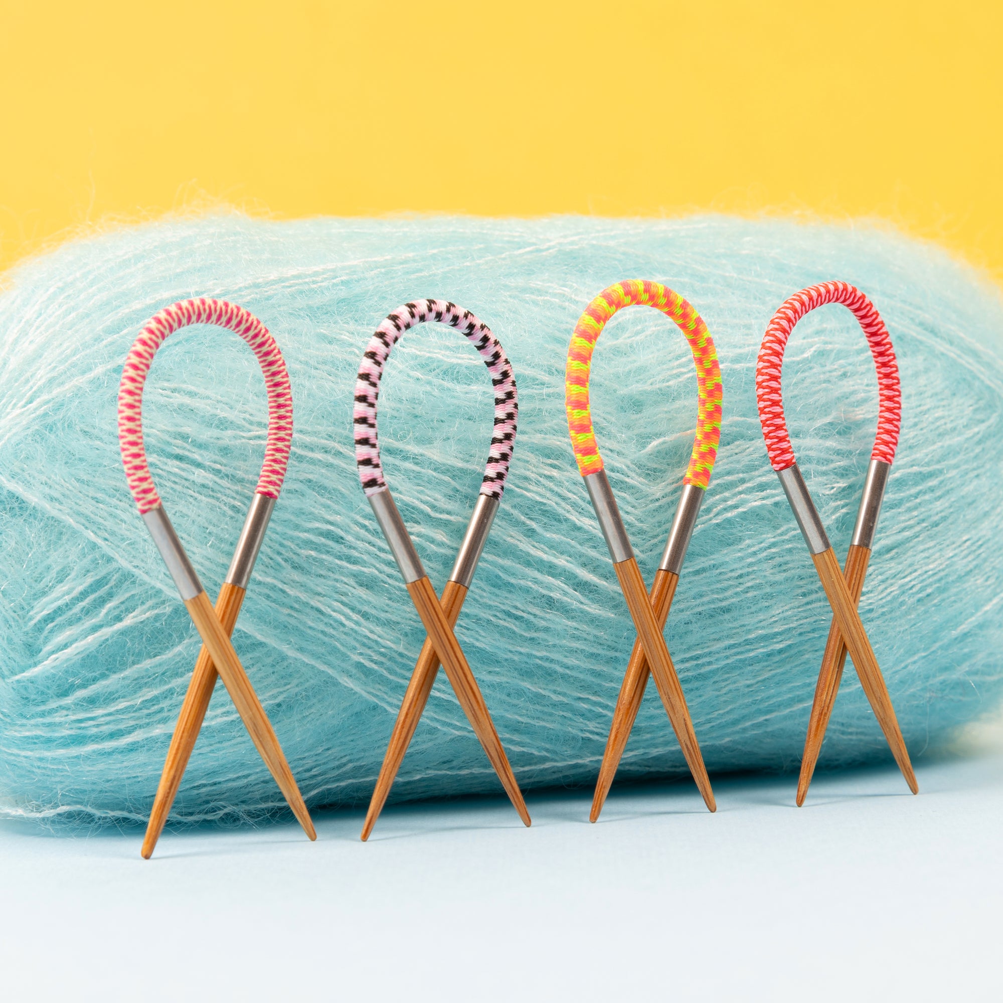 4 Flox Stitch markers placed infront of a ball of blue glowhair yarn. 