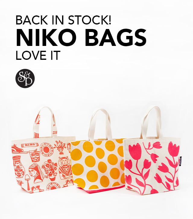 This image advertises that the Niko Bags from the brand Love It are now back in stock at Stephen& Penelope. It features the S&P black logo and three canvas bags on a white background. The bags have  Dutch-inspired drawings in bright orange, yellow, and pink. 